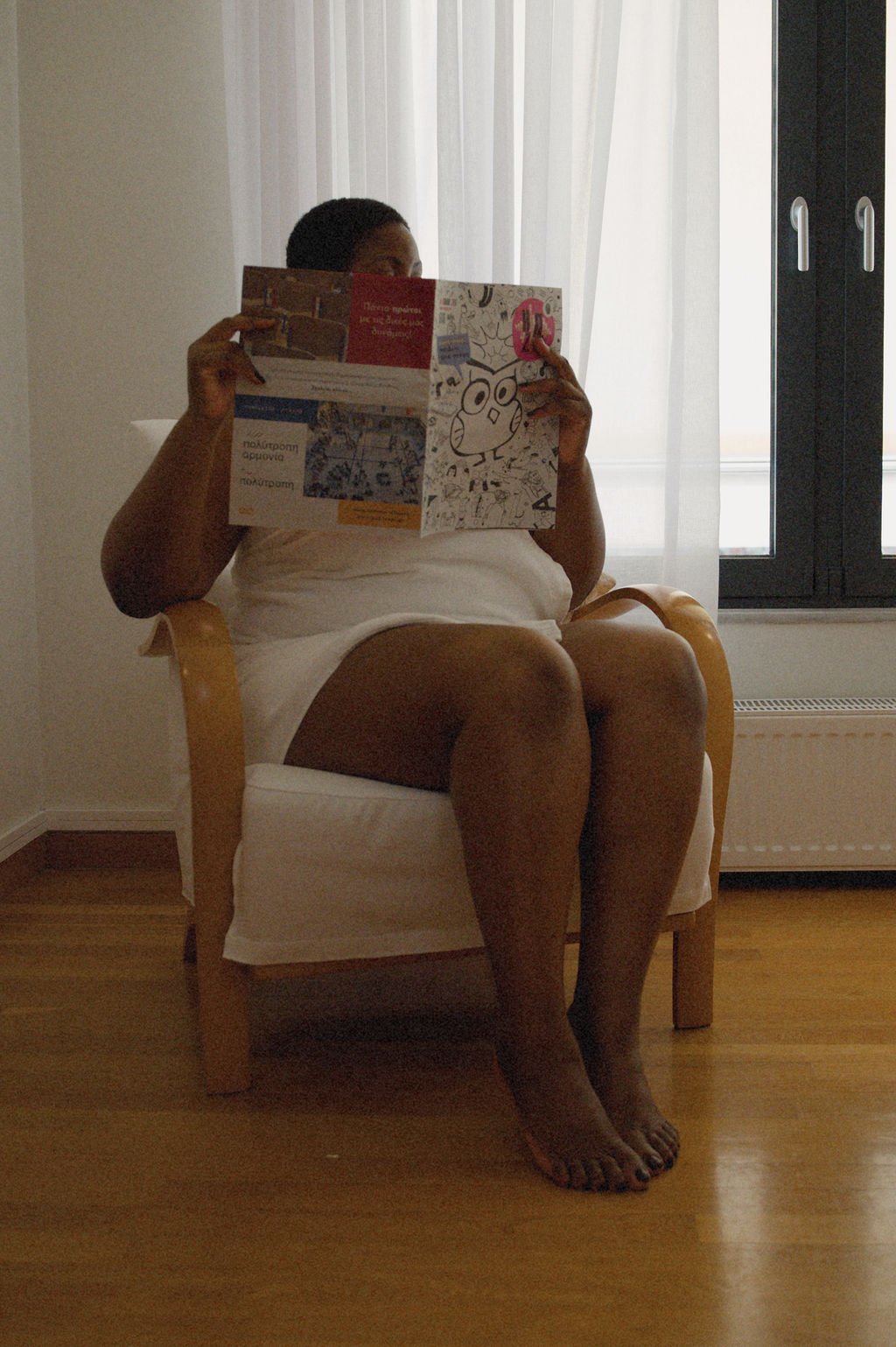 Sable Gold in a chair wearing a white towel, reading a magazine. Luxembourg escort