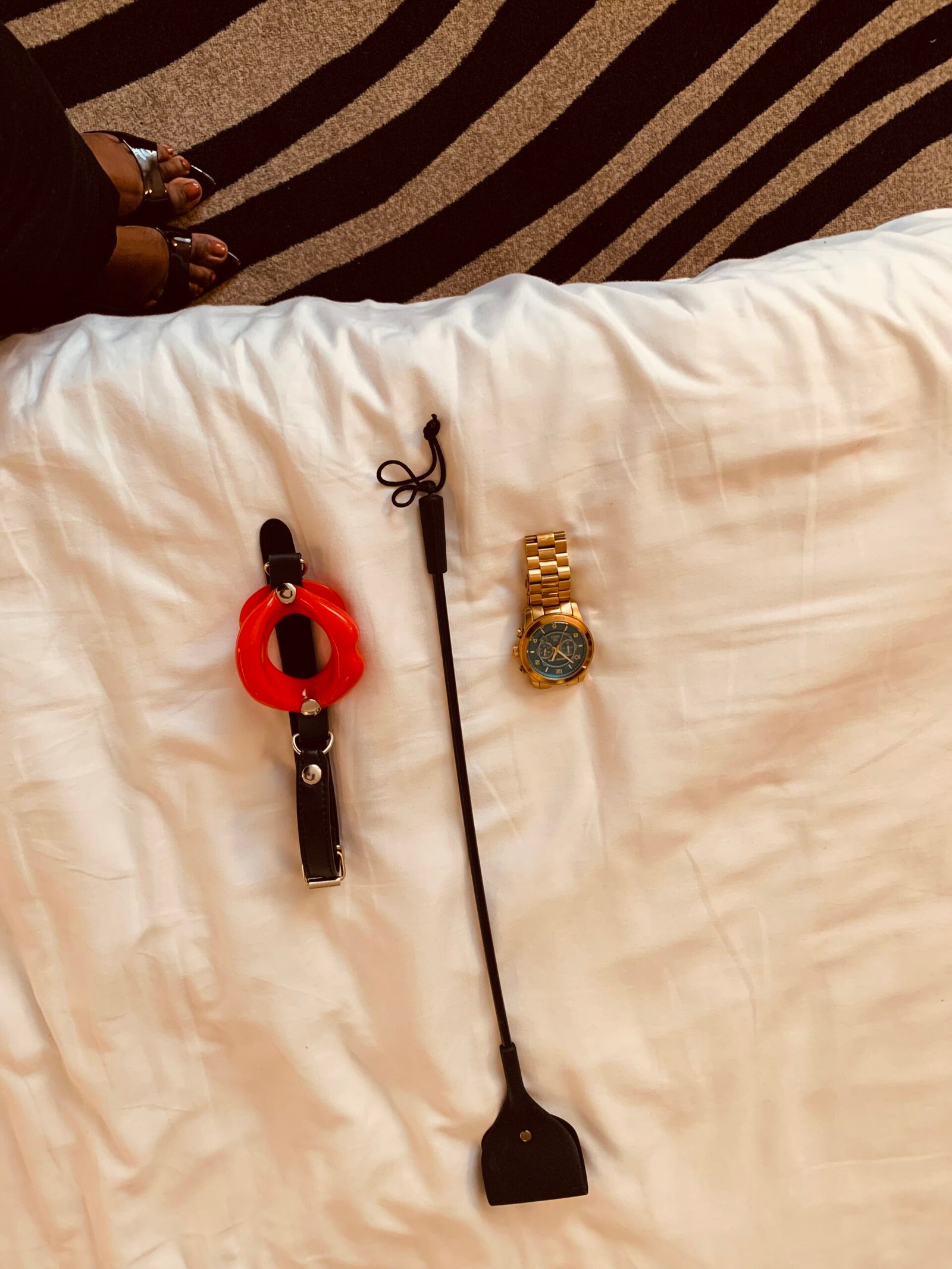 A pair of crossed legs in heels fishnets and heels sitting on a grey chair. Sable Gold, Luxembourg escort