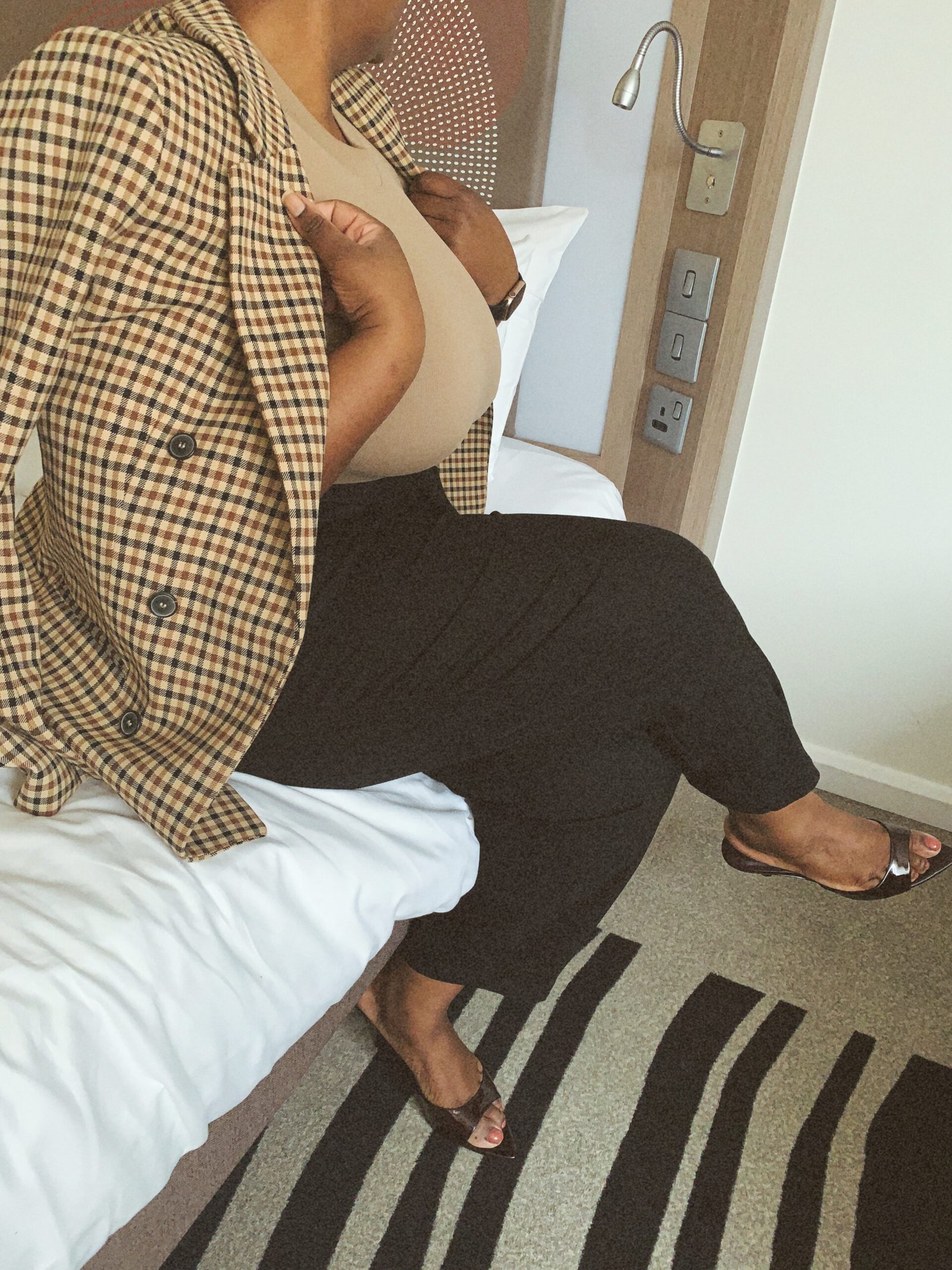 A pair of crossed legs in heels fishnets and heels sitting on a grey chair. Sable Gold, Luxembourg escort